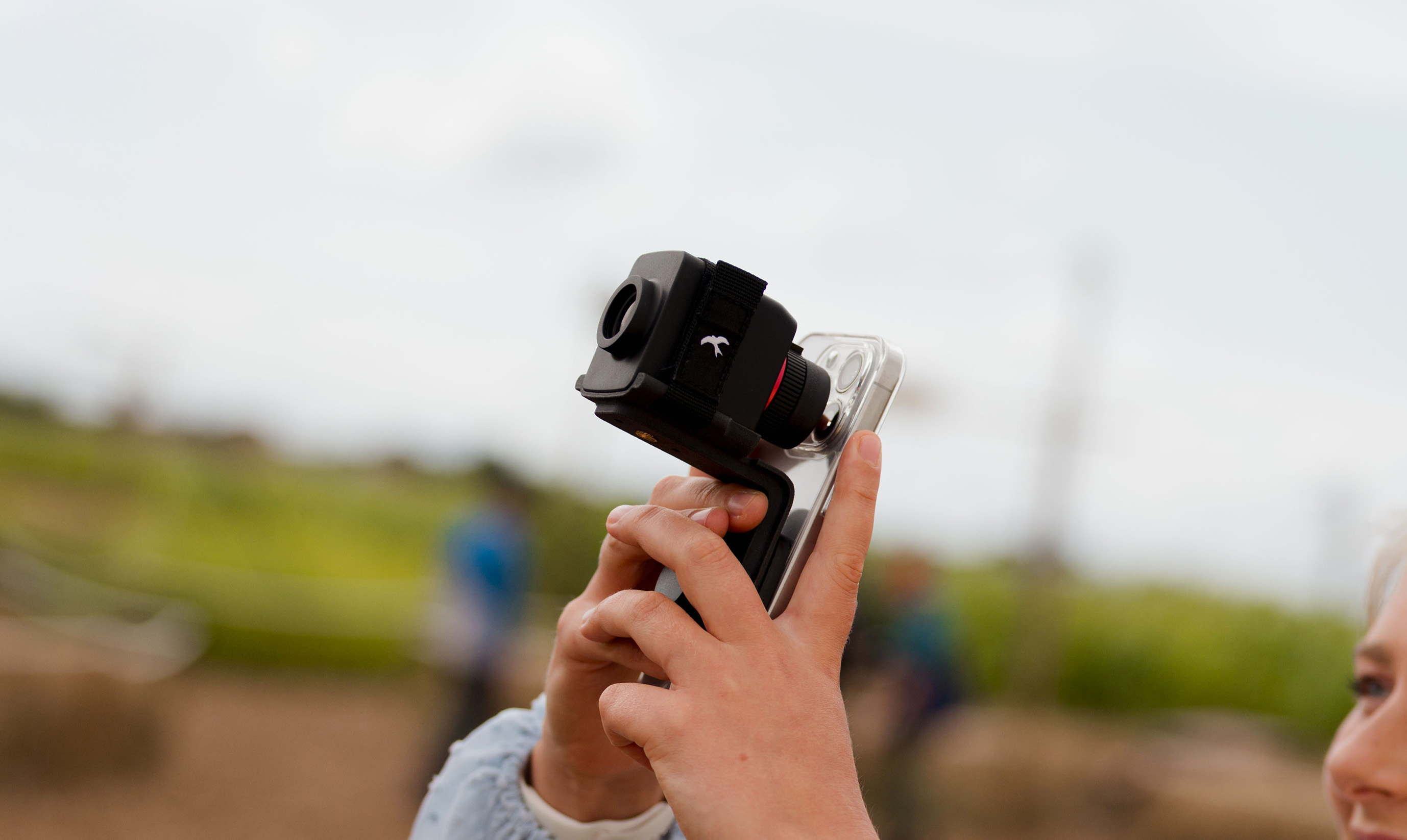 Monoculaire stabilisé Kite Stabi One 10x20 accroché à une smartphone en digiscopie et tenu dans les mains d'une personne