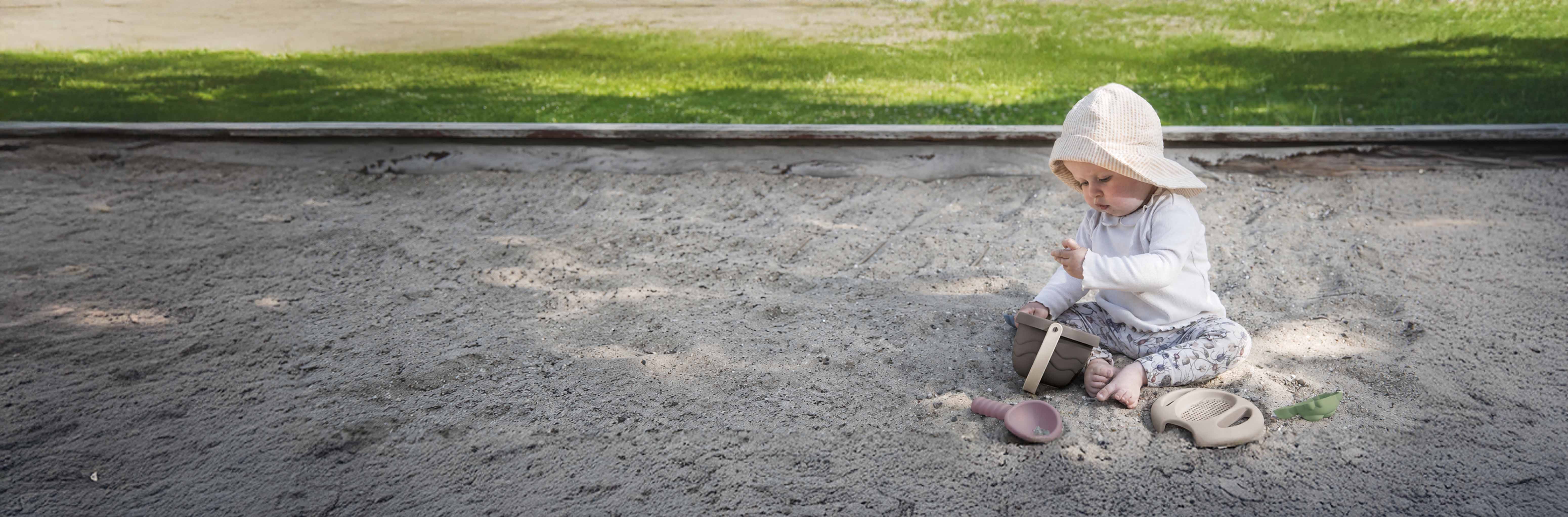 Enfant dans un bac à sable avec des jouets